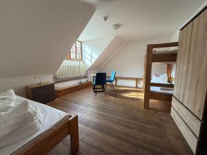 a bedroom with a bunk bed and a desk and chairs at CVJM Peregrinus Herberge in Görlitz