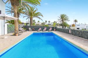 a large blue swimming pool with palm trees in the background at Casa Salinoco in Mácher