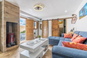 a living room with a blue couch and a tv at Apartamentos cuna del Genil in Güéjar-Sierra