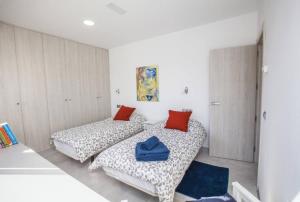 two beds in a room with white walls and red pillows at San Salvador apartamento in Nerja +12 photos