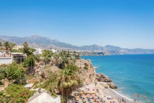 a view of a beach with palm trees and the ocean at San Salvador apartamento in Nerja