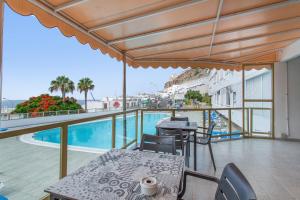 a balcony with a table and chairs and a pool at Vistas al atlantico in Puerto Rico de Gran Canaria