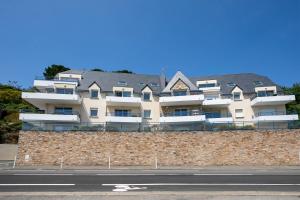 a building on a brick wall next to a street at T2 avec terrasse proche plages in Pléneuf-Val-André