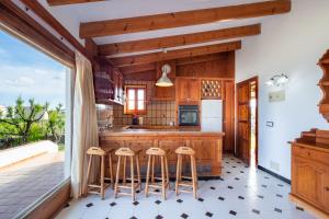a kitchen with wooden cabinets and bar stools at Villa Solivent in Es Mercadal