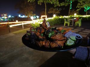 a person is holding a plate of food at Shelby Pawana lake Cottages and Camping in Lonavala