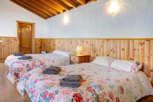 two beds in a room with wooden walls and wooden floors at Mirador de Domingo in Gáldar