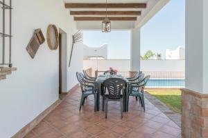 a dining room with a black table and chairs at Villa Conilsur in Conil de la Frontera