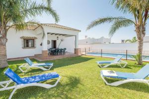 a yard with three lounge chairs and a pool at Villa Conilsur in Conil de la Frontera