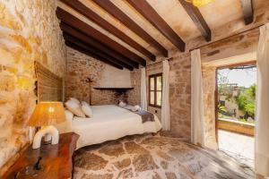 a bedroom with a bed and a stone wall at Es Colomer in Petra +28 photos