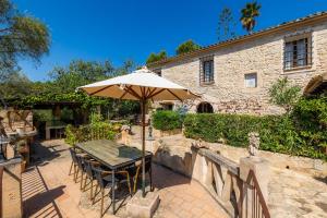 a table with an umbrella in front of a building at Es Colomer in Petra