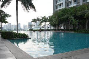a large swimming pool with palm trees and buildings at Cozy Studio Netflix Parking Self Checkin Wifi free wifi 138 in Cyberjaya