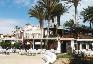 a resort with white tables and chairs and palm trees at Duquesa Beach in Torrevieja