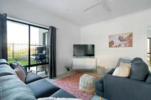 a living room with a couch and a tv at Surfside Getaway Caves Beach Absolute Beachfront in Caves Beach