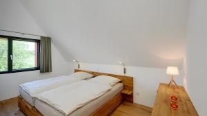 a bedroom with a bed and a table and a window at Ferienhaus Wreechen 25, Haus 1 in Putbus
