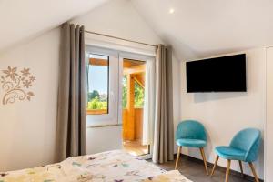 a bedroom with a bed and two chairs and a window at Pur Wohnen - Wohnung Fernsicht in Bad Griesbach