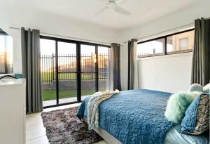 a bedroom with a blue bed and large windows at Surfside Getaway Caves Beach Absolute Beachfront in Caves Beach