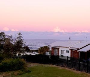 a house on the beach with the ocean in the background at Surfside Getaway Caves Beach Absolute Beachfront in Caves Beach