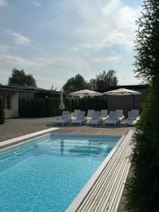 a swimming pool with white chairs and umbrellas at Harmony Cottage in Kyiv