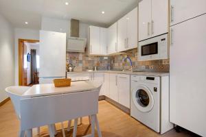 a kitchen with white cabinets and a washer and dryer at Falco 3 in Corralejo