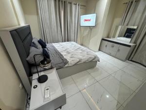 a bedroom with a bed and a desk and a television at IMMEUBLE COSMOS Kintambo in Kinshasa