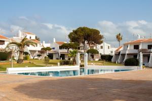 a swimming pool in front of some houses at El Faro 8 in Cala en Bosc