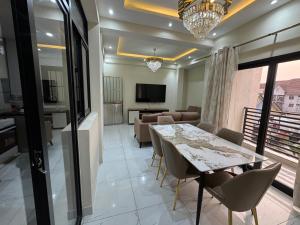 a dining room with a table and chairs and a living room at IMMEUBLE COSMOS Kintambo in Kinshasa