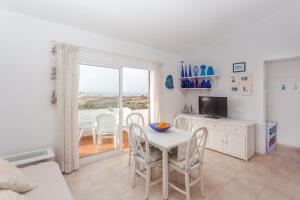 a living room with a table and chairs and a window at El Faro 8 in Cala en Bosc