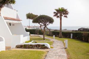 a white house with a pathway leading to the ocean at El Faro 8 in Cala en Bosc