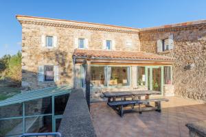 a stone building with a picnic table on a patio at Perles De Aime in Laurac-en-Vivarais