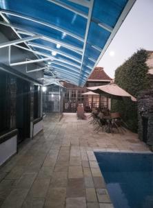 a patio with a pool and umbrellas and a swimming pool at Hotel Pousada da Néia in Cananéia