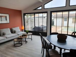a living room with a couch and a table and chairs at Ô'wazo, Jolie Maison, Piscine in Lanton
