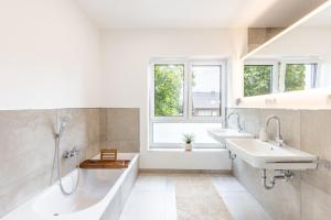 a bathroom with two sinks and a tub and a window at Das Strandhaus 2 in Lembruch +29 photos