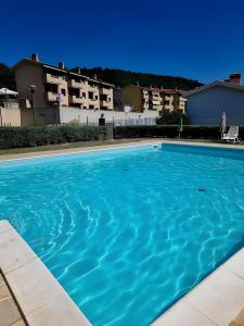 a large blue swimming pool with buildings in the background at Terrazza Catabbio in Catabbio
