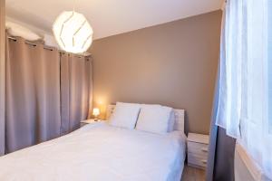 a bedroom with a bed with white sheets and a chandelier at Chalets De L'arriutort 1 - Laruns in Laruns