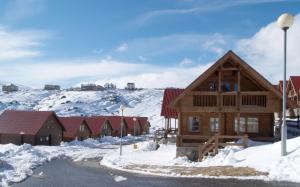 a log cabin in the snow with buildings at Chalet Belfort in Penhas da Saúde