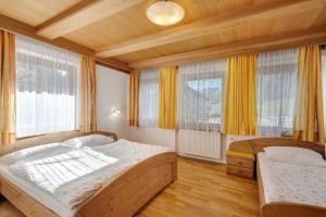a bedroom with two beds and two windows at Hatzlhof Appartements in Vipiteno