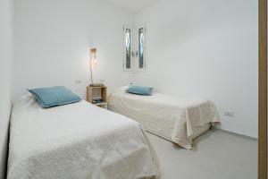 two beds in a room with white walls and blue pillows at Casa Dina - by And Service in Golfo Aranci