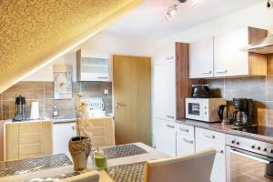 a kitchen with white cabinets and a table with chairs at Fewo Wilhelmshaven Langewerth in Wilhelmshaven