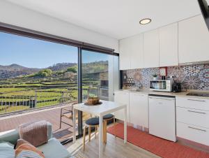 a kitchen with white cabinets and a table with a view at Casa Dona Florinda in Ermida