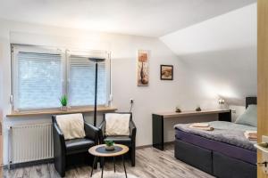 a bedroom with a bed and two chairs and a window at Fewo Wilhelmshaven Langewerth in Wilhelmshaven