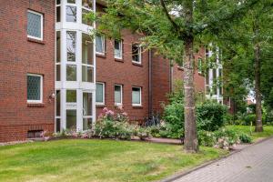 a brick building with a grass yard in front of it at Sonne, Wind und Wetter in Wurster Nordseeküste