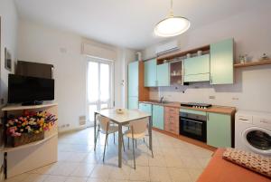 a kitchen with green cabinets and a table with chairs at Trilocale Mazzini con 2 balconi in Varazze