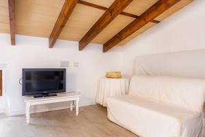 a living room with a tv and a white couch at Ca la Senyora dels Arbres in Artá