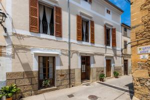 a building with wooden shutters on a street at Ca la Senyora dels Arbres in Artá
