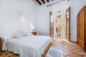 a bedroom with a white bed and a large window at Ca la Senyora dels Arbres in Artá +33 photos
