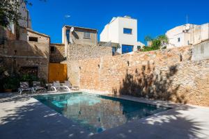 a swimming pool in front of a stone wall at Ca la Senyora dels Arbres in Artá