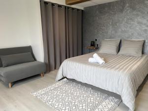 a bedroom with a large bed and a chair at Appartement Gorges du Tarn in Mostuéjouls