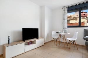 a living room with a flat screen tv on a cabinet at El Refugio in Sardina