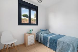 a bedroom with a bed and a chair and a window at El Refugio in Sardina