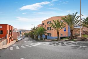 an empty street with palm trees and a building at El Refugio in Sardina
